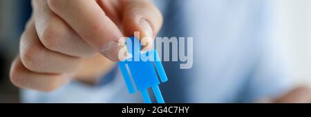 Male hand putting blue toy man to wooden closeup Stock Photo
