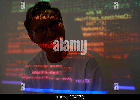 Computer hacker sitting in dark room and smiling he working with computer program Stock Photo