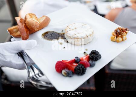 Grilled Camambert with berries and lingonberry sauce served in a restaurant. Hospitality and catering service concept Stock Photo