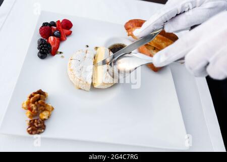 Grilled Camambert with berries and lingonberry sauce served in a restaurant. Hospitality and catering service concept Stock Photo