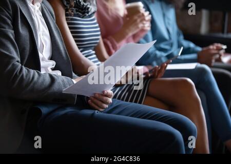 Closeup unrecognizable young multiracial people sitting in line on sofa. Stock Photo