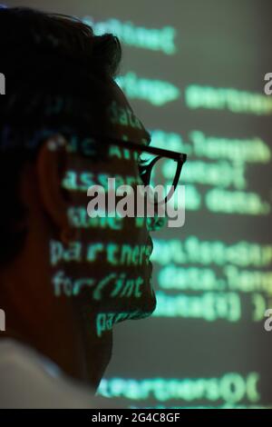 Close-up of man in eyeglasses sitting at presentation of new software in dark office Stock Photo