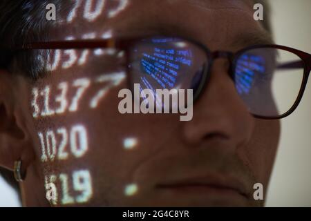 Close-up of computer hacker in eyeglasses working with computer code reflecting in his eyeglasses Stock Photo