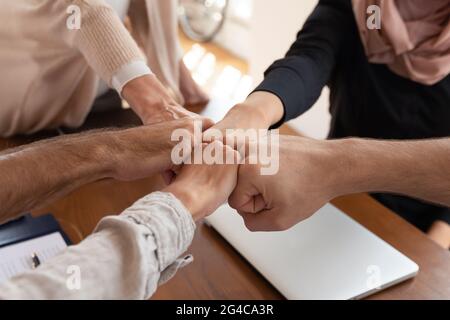 Close up motivated diverse employees joining fists at corporate meeting Stock Photo