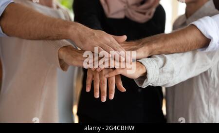 Close up motivated multiethnic employees team putting hands together Stock Photo