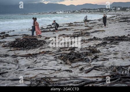 A couple with a baby bump poses for a photograph on Kommetjie's Long Beach at dusk, near Cape Town, in South Africa's Western Cape. Stock Photo