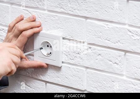 Electrician mounting electric sockets on the white wall indoors Stock Photo