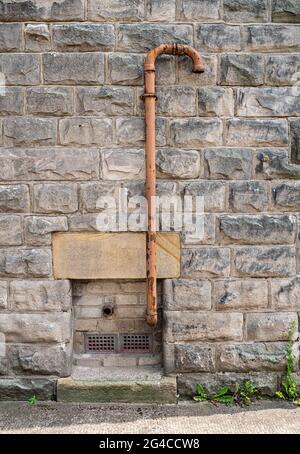Yellow painted pipe attached to wall of building Stock Photo