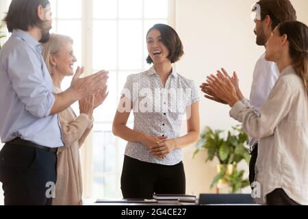 Happy employees applauding, thanking Asian businesswoman executive at meeting Stock Photo