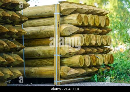 pallet with long round natural wooden fence posts with a sharpened tip ...