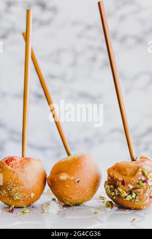Caramel, Toffee Apples on sticks, light and bright white background, easy to make sweet desserts with fresh organic fruit Stock Photo