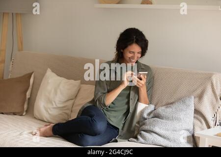 Overjoyed woman using smartphone, laughing, having fun with gadget Stock Photo