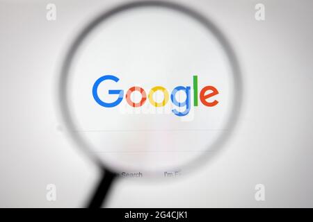 Google company logo on a website, seen on a computer screen through a magnifying glass. Stock Photo