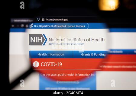 NIH National Institute of Health company logo on a website, seen on a computer screen through a magnifying glass. Stock Photo