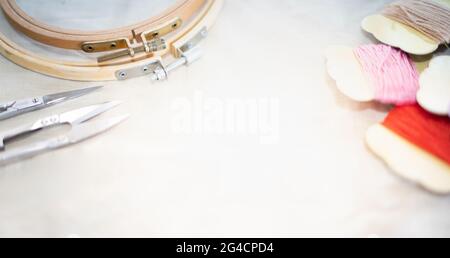 Selective focus of The tailor's workplace with threads, scissors, wood frame, spools, fabric put on white background top view space for text. Stock Photo