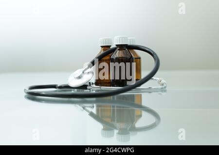 A stethoscope and three medicine bottles lie on a glass table Stock Photo