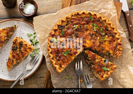 Bacon, mushroom and spinach quiche with cheese and herbs Stock Photo