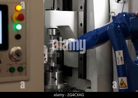 CNC machine and robotic arm loading and unloading workpieces. Selective focus. Stock Photo