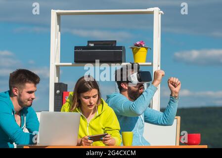 Brainstorming business people. Team of young business people testing virtual reality headset and discussing new visual experience. Stock Photo