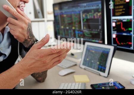 Close-up image of trader analyzing stock market data and talking on phone with client or coworker Stock Photo