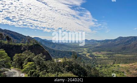 Aerial of valley between mountain ranges under a cloudy blue sky