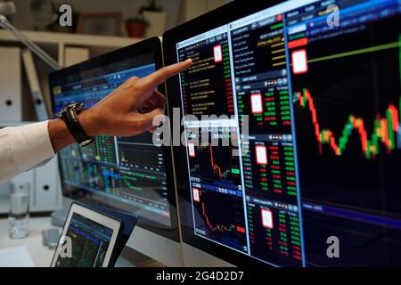 Close-up image of trader is pointing at graphs on computer screen and analyzing data and prices of assets Stock Photo