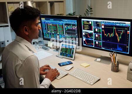 Stock broker working on computer and analyzing charts and prices on screens of various gadgets Stock Photo