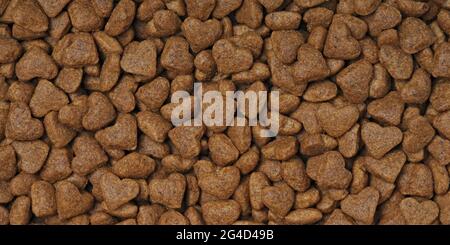 Heart shaped dryed food for cats and dogs. Panoramic background texture. Stock Photo