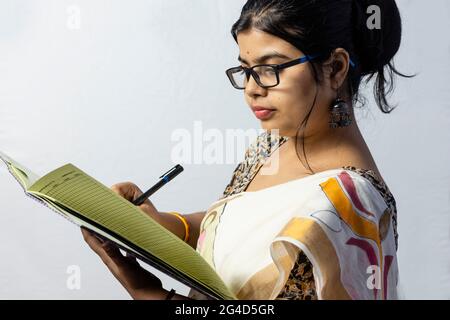 Isolated on white background an Indian office woman in saree writing on notebook with pen side facing Stock Photo