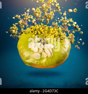 Glazed donut with flying pistachio on blue background Stock Photo