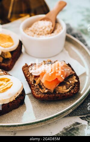 Toasted breads with poached eggs, avocado and salmon. Guacamole sandwiches. Healthy breakfast. Olive oil. Sesame seeds. Vegetarian healthy eating. Die Stock Photo