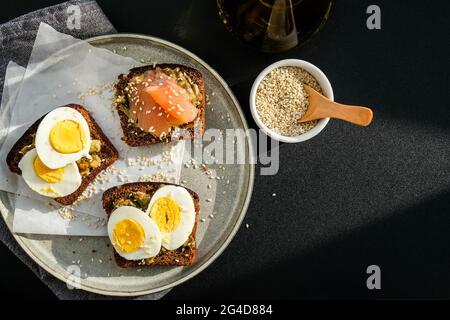 Toasted breads with poached eggs, avocado and salmon. Guacamole sandwiches. Healthy breakfast. Olive oil. Sesame seeds. Vegetarian healthy eating. Die Stock Photo