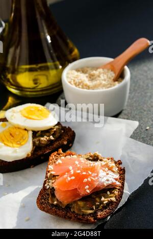 Toasted breads with poached eggs, avocado and salmon. Guacamole sandwiches. Healthy breakfast. Olive oil. Sesame seeds. Vegetarian healthy eating. Die Stock Photo