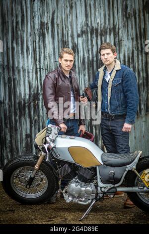 Two man dressed in jeans and leather jacket  talking and standing together beside motorcycle. Stock Photo