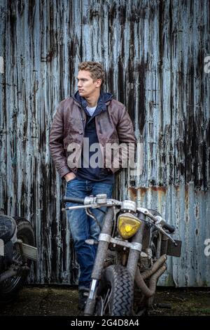 man dressed in jeans and leather jacket with custom cafe racer motorcycle Stock Photo