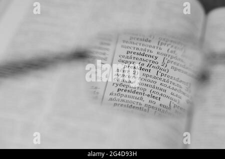 Reading glasses and an open book in close-up. Old Russian-English Dictionary. Selective Focus on the word PRESIDENT. Stock Photo