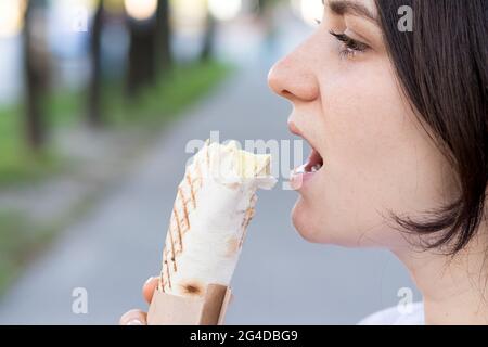 Beautiful woman eating shawarma on a city street. Fast food on the way to work or school. Place for text.