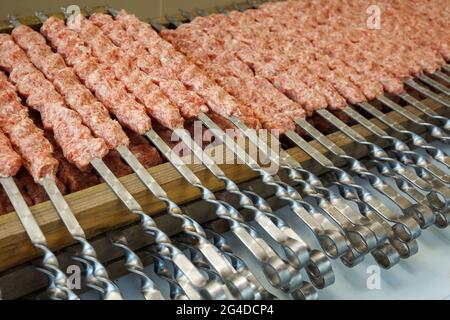 Raw sausages strung on skewers before grilling Stock Photo