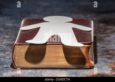 An old book with a silhouette of a man lying on it, made of paper. Bookmark Stock Photo