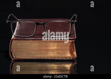 An old book with glasses lying on it Stock Photo