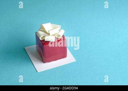 Gatou cake in the form and shape of gift box wrapped with ribbon. On blue background, copy space. Stock Photo