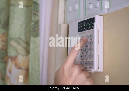 Woman entering code pin on home alarm system keypad. Close up shot. Home security concept. Stock Photo