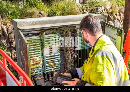 A telecoms engineer works on solving connection issues in a street cabinet, St Agnes Cornwall England UK Stock Photo