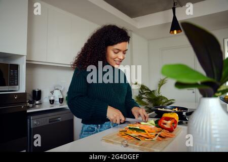 African American woman chopping vegetables in the kitchen. Woman preparing food. High quality photo  Stock Photo