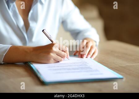 Close up of woman hands signing paper contract on table at home or office Stock Photo
