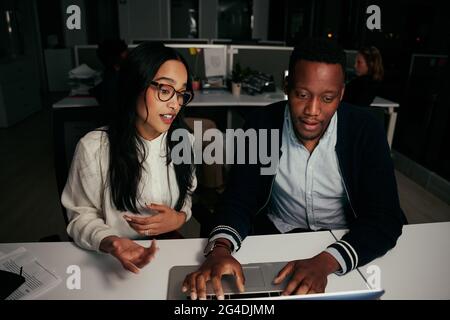 Diverse business colleagues discussing while working together using laptop in office Stock Photo