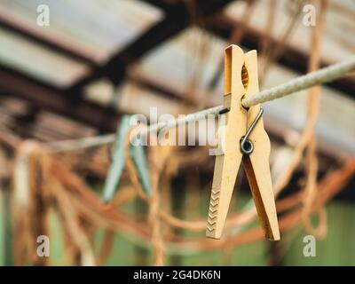 Selective focus on an old yellow clothespin on a rope close-up. Blurred background. Stock Photo