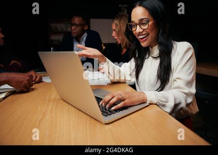 Portrait of excited young businesswoman wearing eyeglasses working on laptop in the corporate business Stock Photo