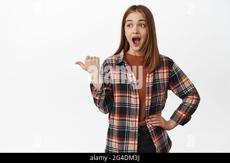 Portrait of young attractive woman drop jaw from excitement and awe,  pointing and looking left at impressive advertisement, big announcement  aside Stock Photo - Alamy