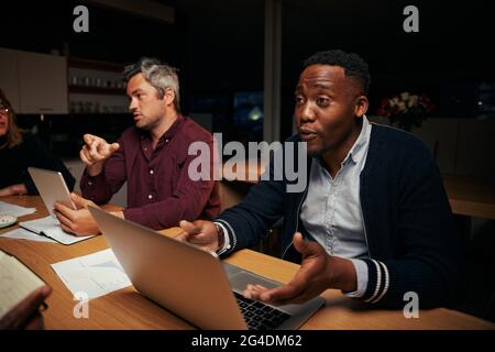 Two diverse businessmen using laptop and digital tablet discussing work in office Stock Photo